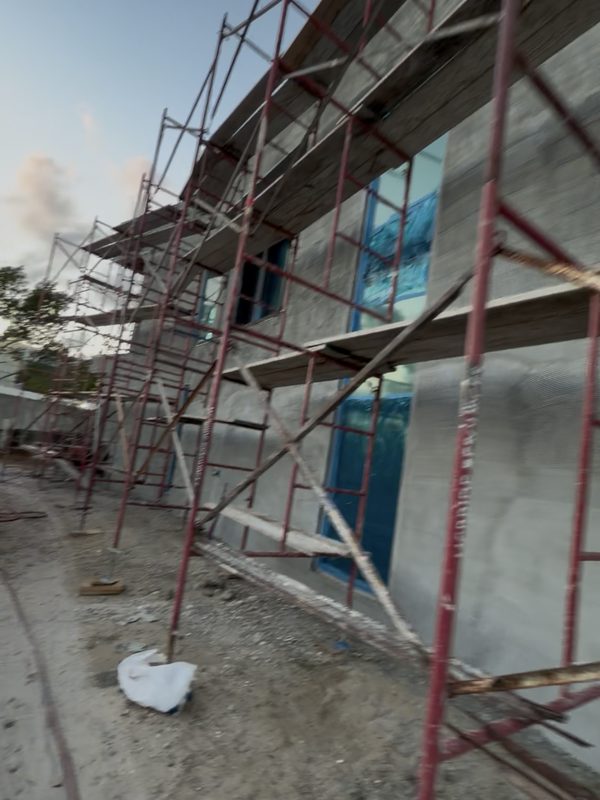 Two storey stucco exterior under scaffolding being prepared for coating